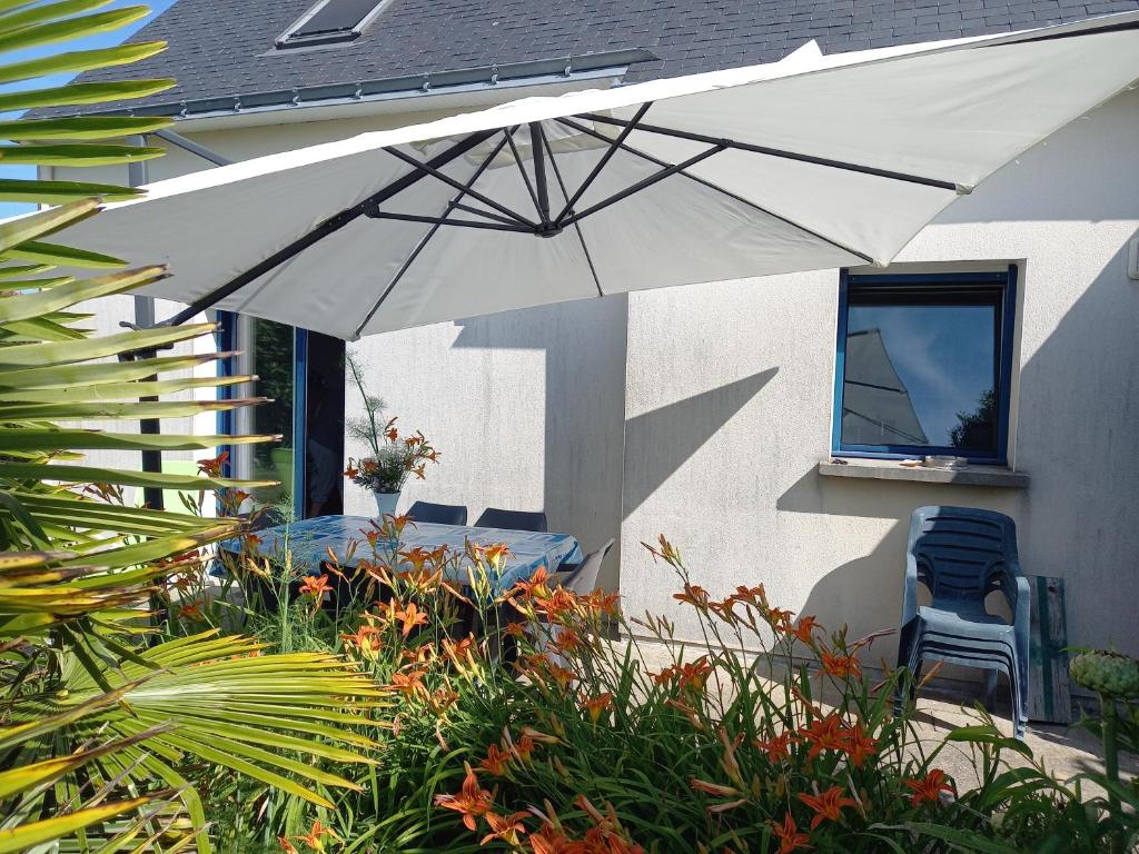 un parasol blanc assis sur le côté d'une maison dans l'établissement Maison 8p sud bretagne 5km de la mer, à Saint-Molf