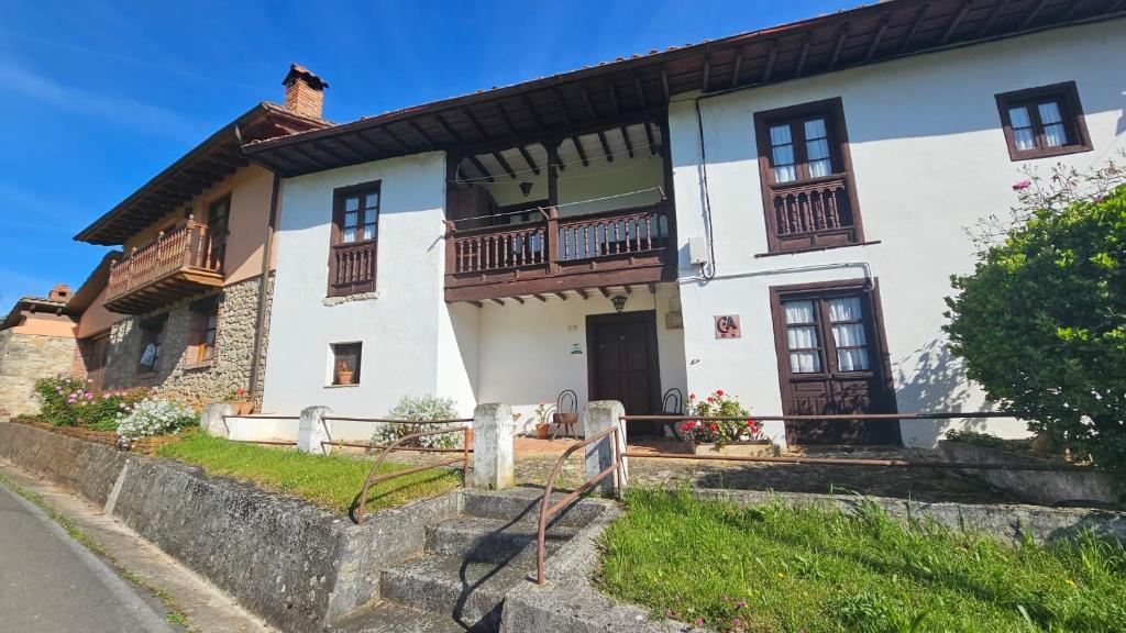 a large white house with wooden balconies on it at Vivienda Vacacional Casa Casenti in Villanueva de Ardisana
