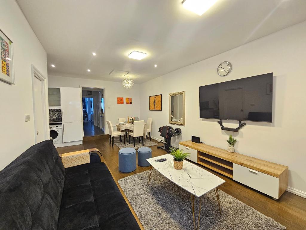 a living room with a black couch and a flat screen tv at Delightful 2 Bedroom Apartment! in London