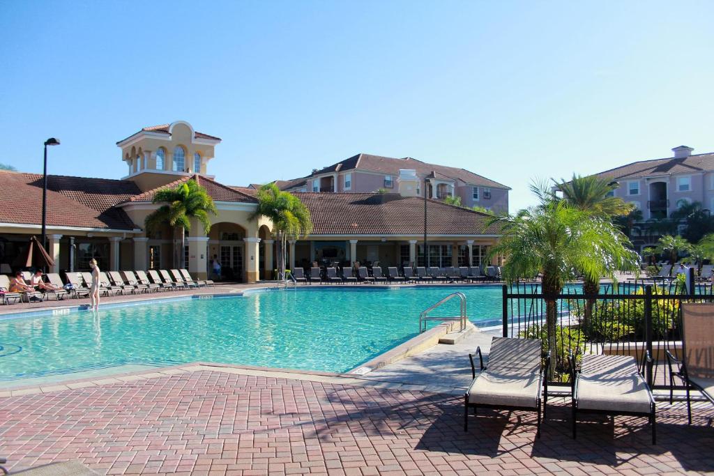 a swimming pool with chairs and a building at Vista Cay Inn in Orlando