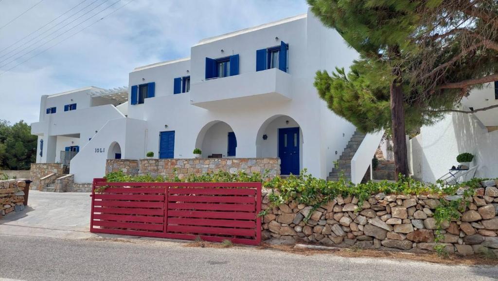 uma casa com janelas azuis e um portão vermelho em Ioli Apartments em Alopronia