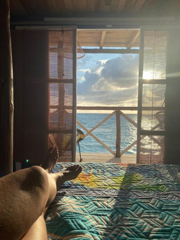 a person laying on a bed looking out at the ocean at Tequila SunBeach Baru Eco-Hotel in Barú