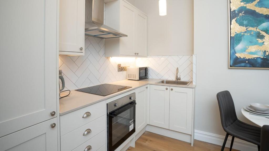 a small kitchen with white cabinets and a table at Modern 2 BDR apartment at Queens by Belfast City Breaks in Belfast
