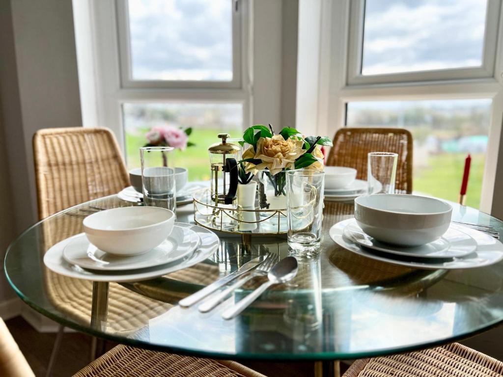 un tavolo di vetro con piatti e ciotole sopra di Luxurious & Modern Apartment a Hawkhead