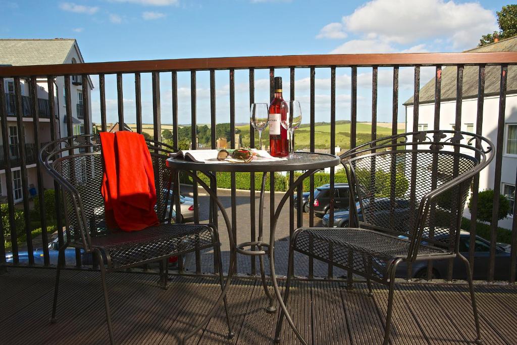 a table with a bottle of wine and two chairs on a balcony at 13 Combehaven in Salcombe