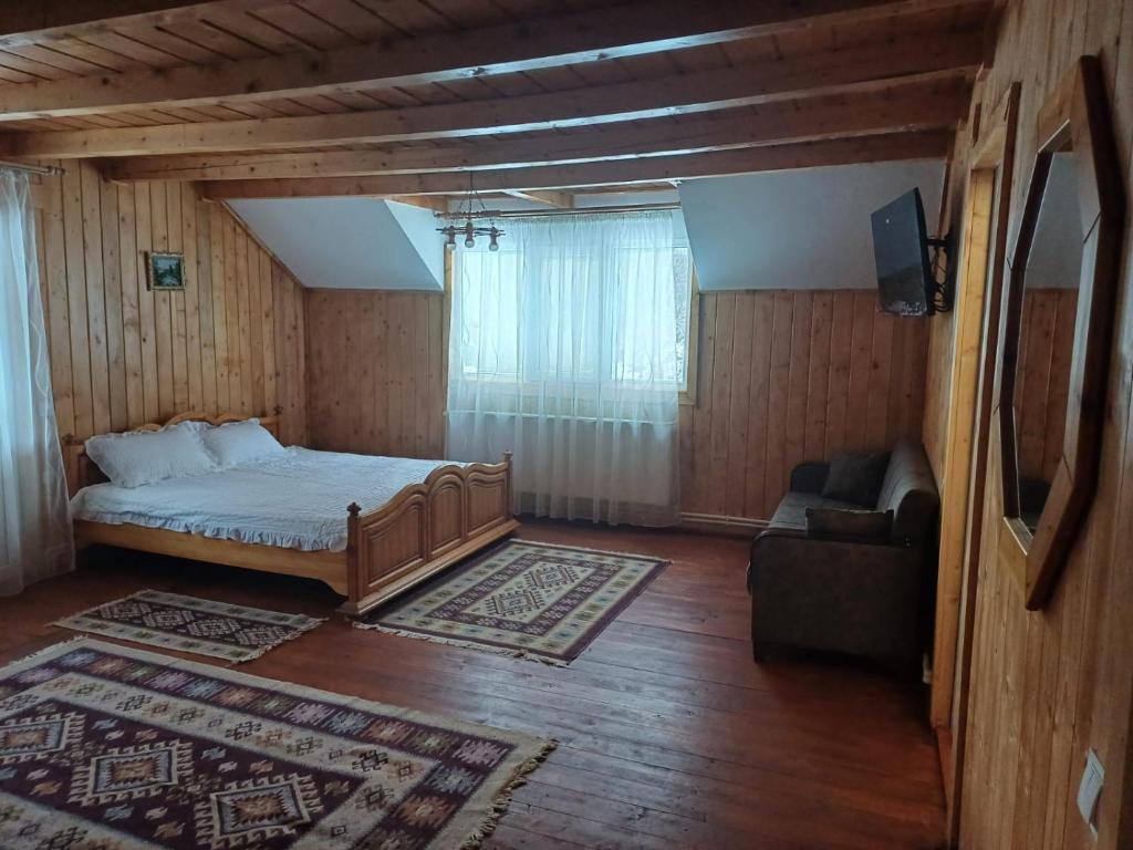 een slaapkamer met een bed, een bank en een televisie bij Sătic Casa Maria in Sătic