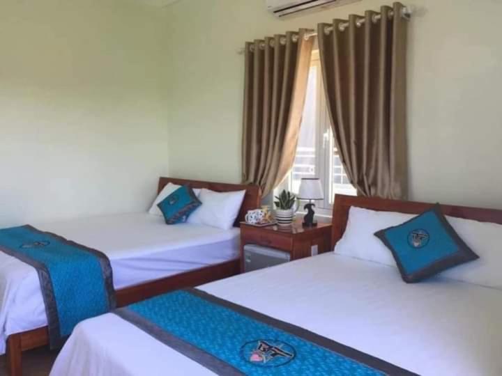 a hotel room with two beds and a window at Nana Lee Homestay Phong Nha in Cừ Lạc
