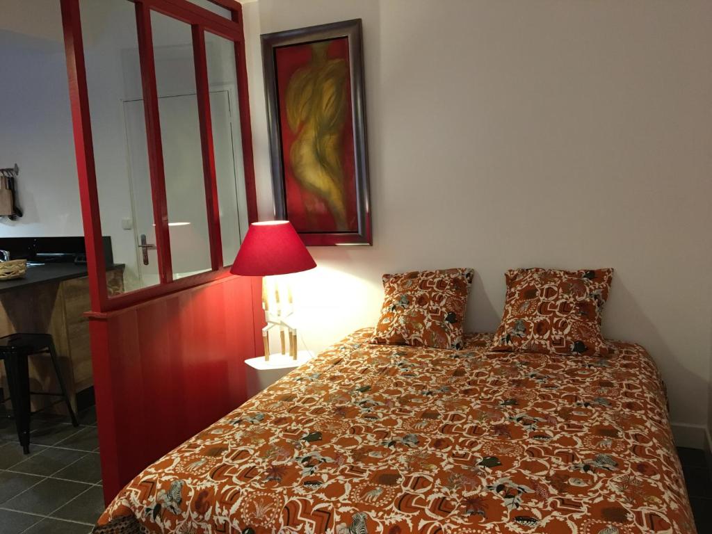um quarto com uma cama com uma colcha vermelha e um candeeiro em L’Atelier cosy em Auxerre