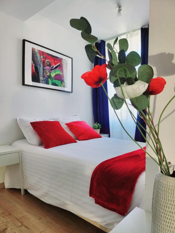 une chambre avec un lit blanc avec des oreillers rouges dans l'établissement Appartement de charme, à Toulouse