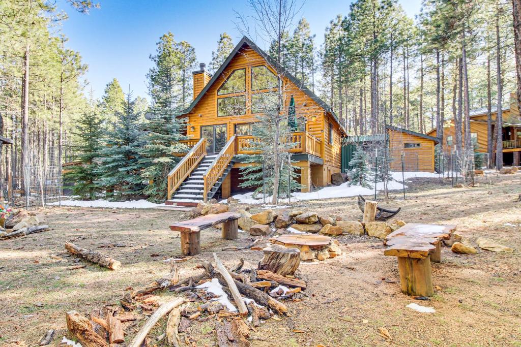 a log cabin in the woods with logs and picnic tables at Family-Friendly Cabin with Fire Pit in Forest Lakes in Forest Lakes Estates