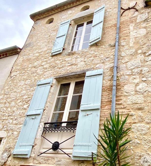 un bâtiment en pierre avec des volets bleus et une fenêtre dans l'établissement Maison St. Clair, à Monflanquin