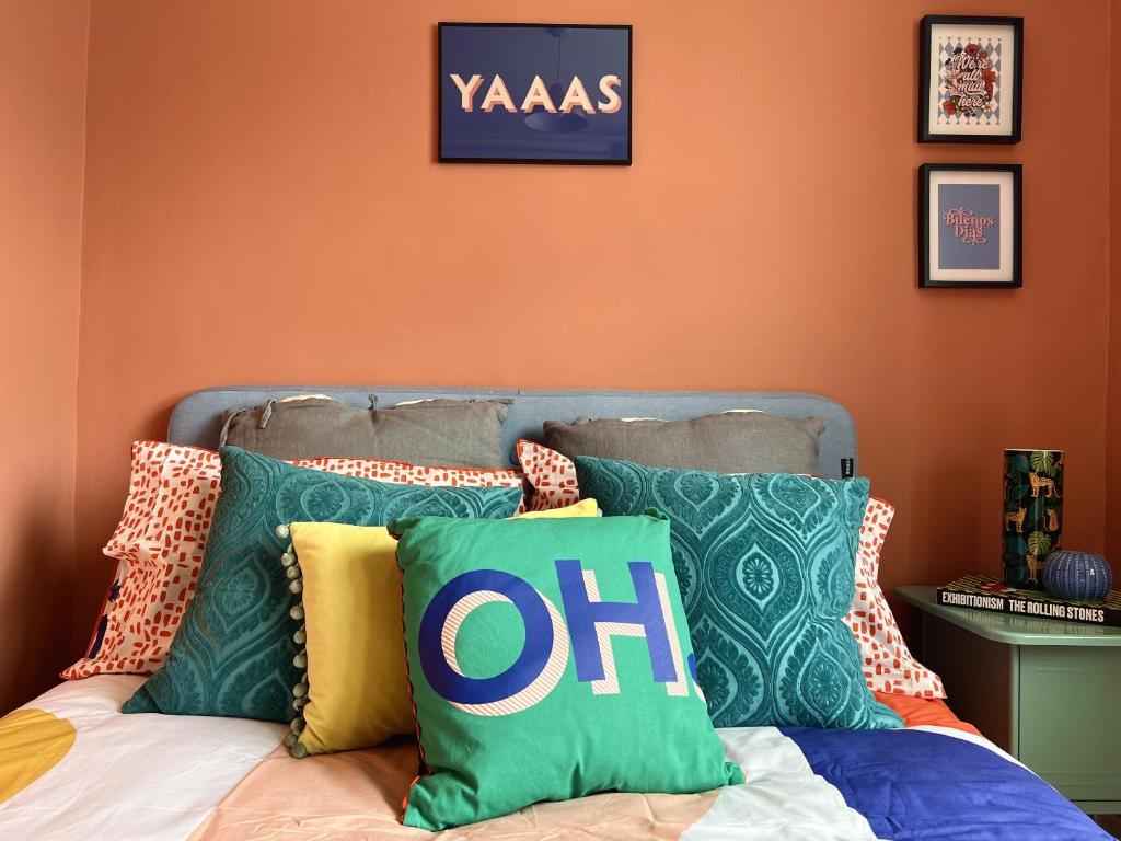 un letto con cuscini colorati sopra di Vibrant City Cottage in Camberwell a Londra