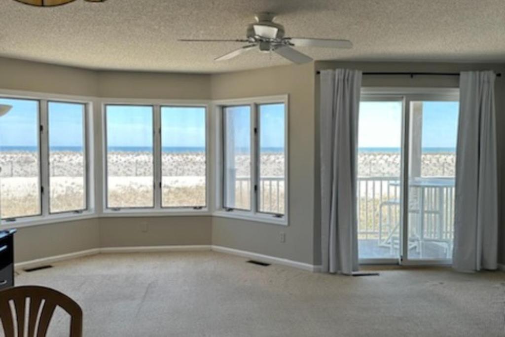 una sala de estar vacía con grandes ventanas y el océano en Sea Breeze Beach View, en Seaside Heights