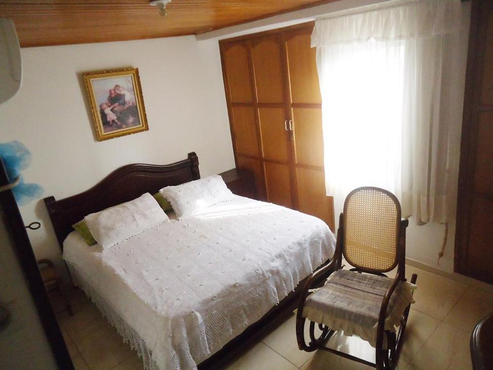 een slaapkamer met een bed, een stoel en een raam bij Roberto Carlos in Valledupar