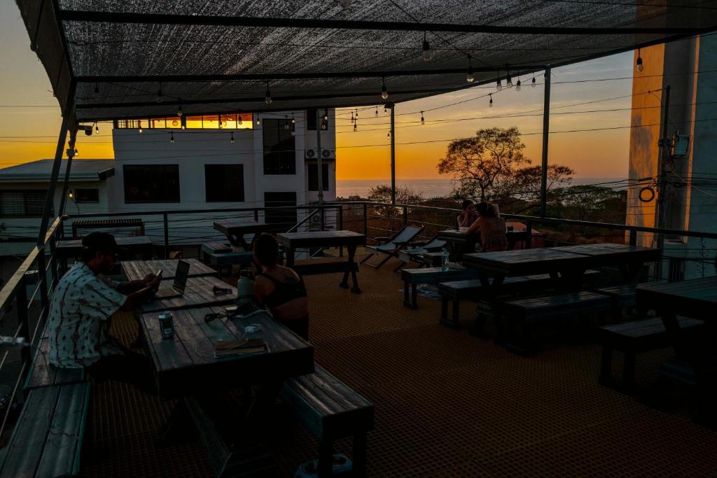 un grupo de personas sentadas en mesas en un balcón en Pupa House en Tamarindo