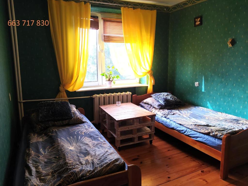 a room with two beds and a table and a window at Pokoje Inowrocław Zarembiny in Inowrocław