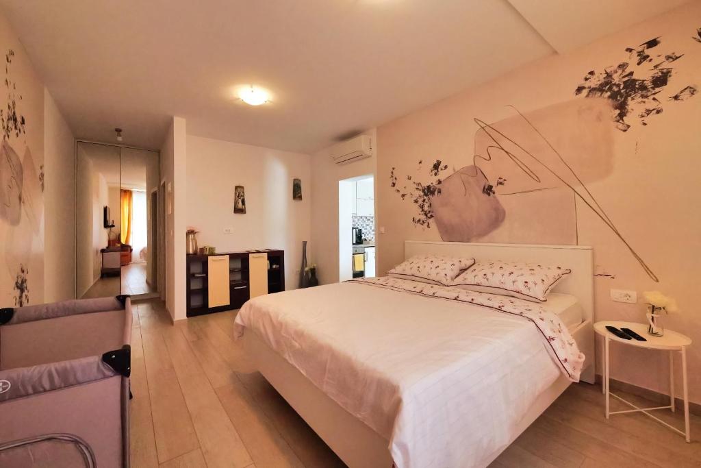 a bedroom with a large white bed with a painting on the wall at Dubrovnik Airport Apartment Pascal in Močići