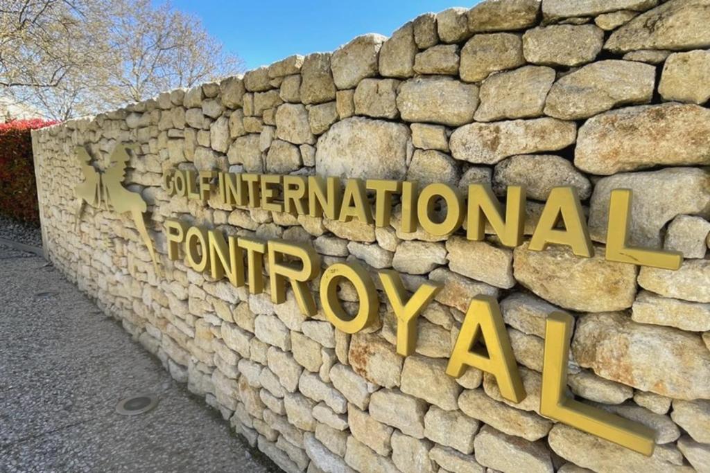 Una pared de piedra con un signo que lee a nivel internacional y regular en Mazet Castel in Pont-Royal en Mallemort