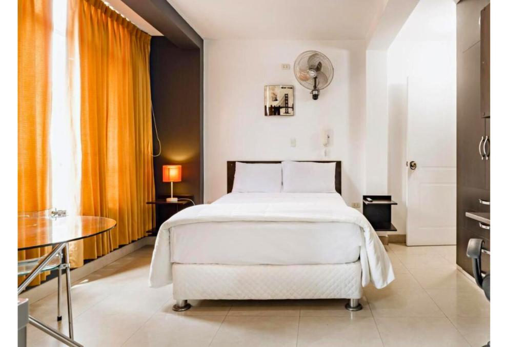 1 dormitorio con cama blanca y mesa en ESCALA BUSINESS HOTEL, en Chiclayo