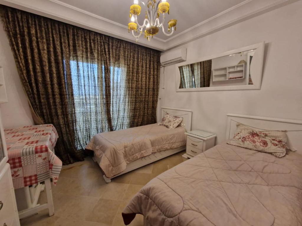 a bedroom with two beds and a chandelier at Diar Tunis Carthage II in Ariana