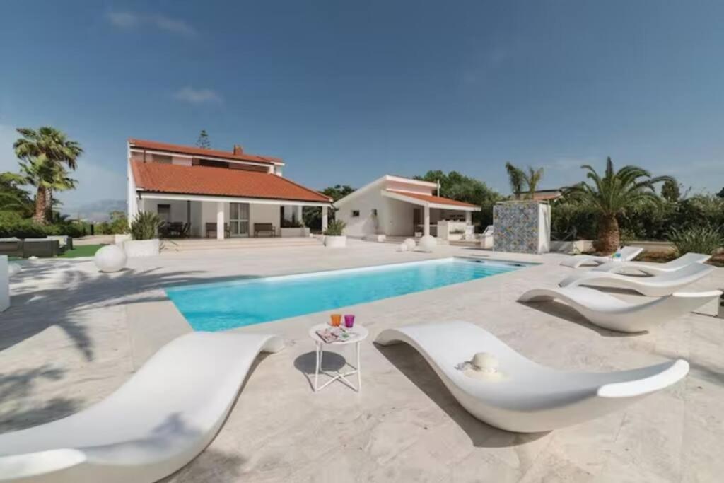 - une piscine avec des chaises blanches en face d'une maison dans l'établissement Villa delle Sterlizie con piscina e jacuzzi by Le Dhome Sicily, à Partinico