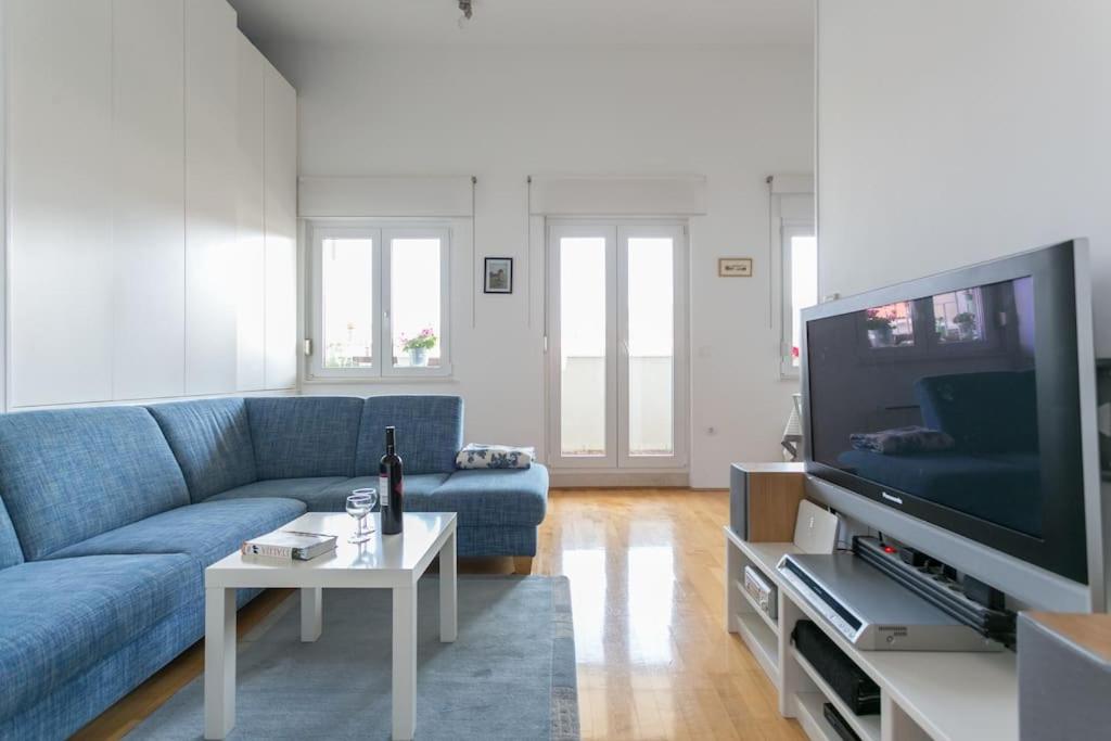 een woonkamer met een blauwe bank en een tv bij Swanky Gem in Dubrovnik