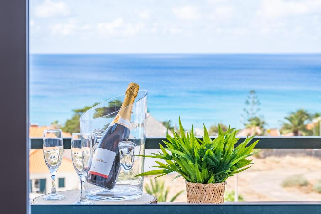 a bottle of wine and glasses on a table with the beach at Villa Bella Mar by Madeira Sun Travel in Porto Santo