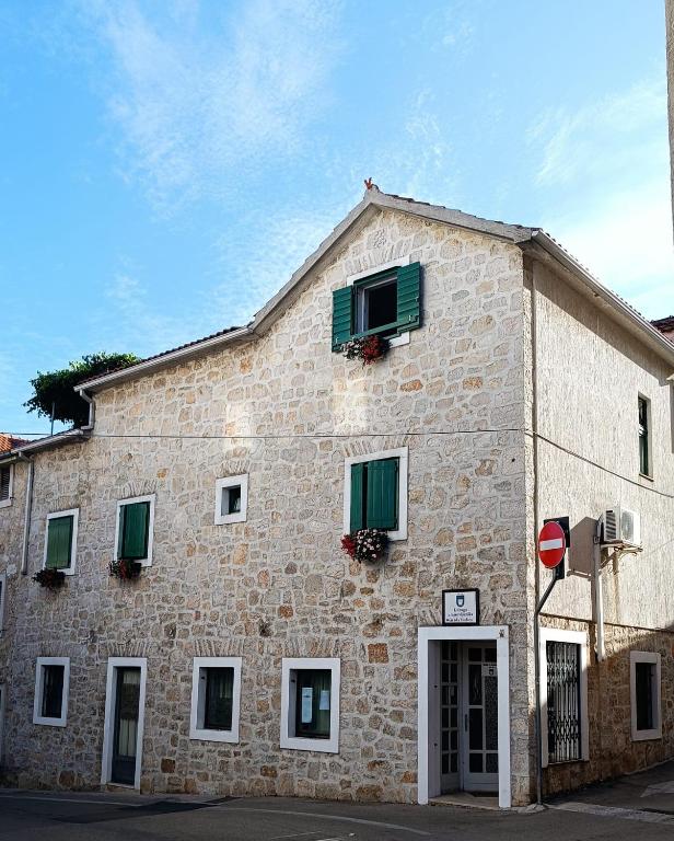 a large stone building with green shutters on it at Apartment Udovičić Center in Vodice