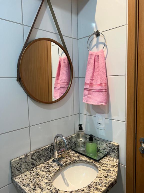 Apartamento aconchegante em Betim في بيتيم: حوض الحمام مع مرآة ومنشفة وردية