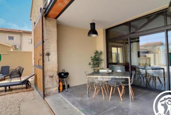 een kamer met een tafel en stoelen op een patio bij Le Dormadou des tilleuls in Graveson
