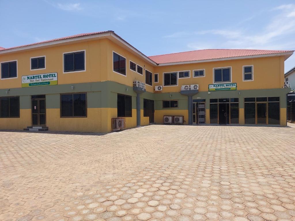 a large yellow building with a driveway in front of it at NABTEL HOTEL in Spintex