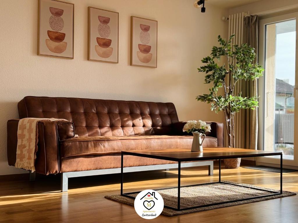 un sofá de cuero marrón en una sala de estar con mesa en Family M Apartments 7 en Sempach