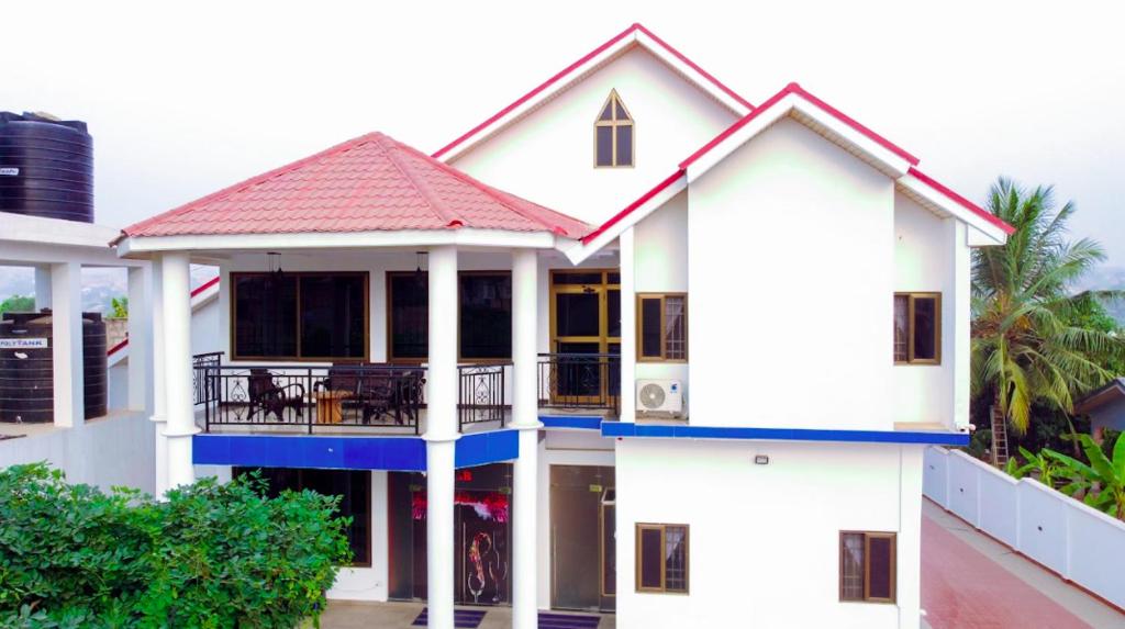 een wit huis met een rood dak bij MT Everest Hotel Ghana in Kwabenyan