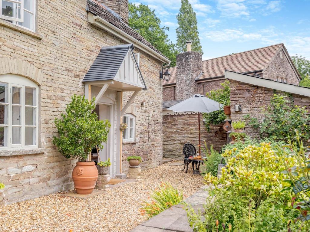 a brick house with an umbrella and a patio at 1 Bed in Hay-on-Wye 93134 in Bacton