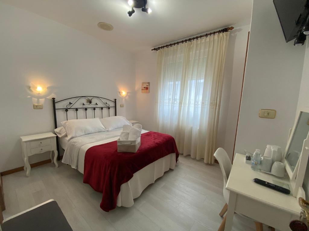 1 dormitorio con 1 cama con manta roja y escritorio en Hotel Carabela La Pinta en Baiona