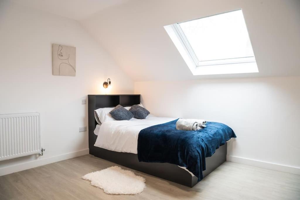 a bedroom with a bed with a blue blanket and a window at Modern Studio: Old Trafford in Manchester