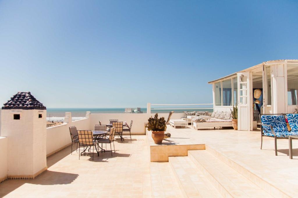 a balcony with chairs and tables and the ocean at Blue Kaouki in Sidi Kaouki