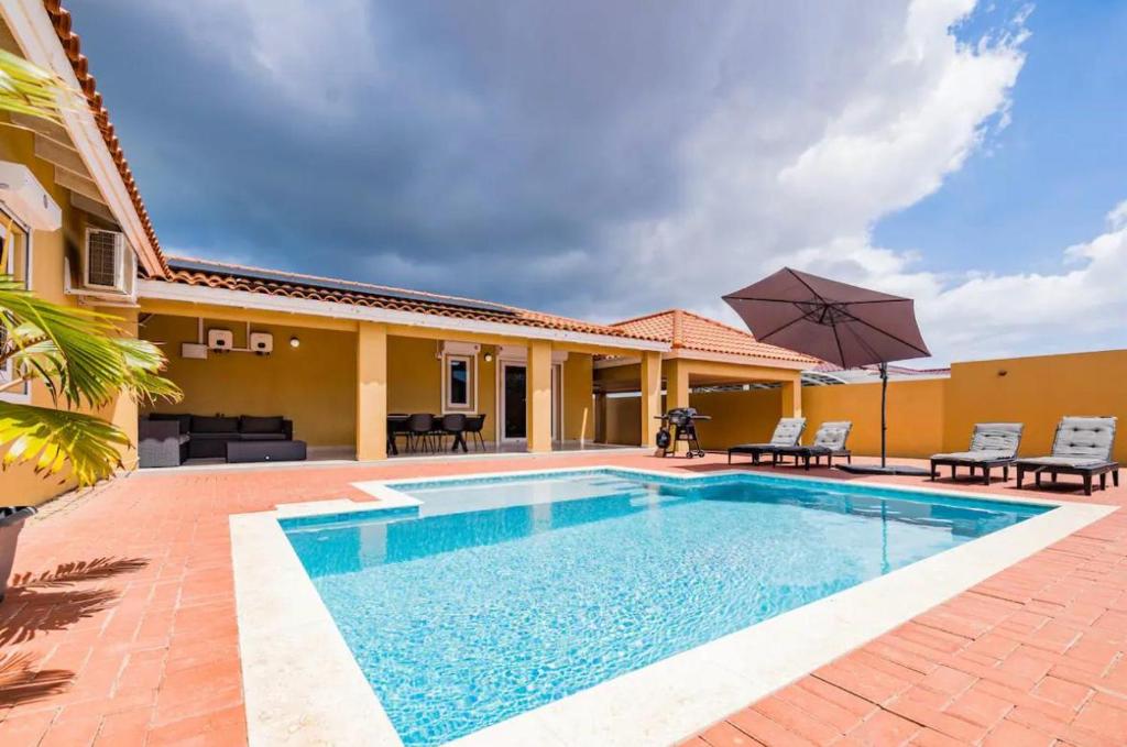 a swimming pool in front of a house at Island Oasis Villa in Noord