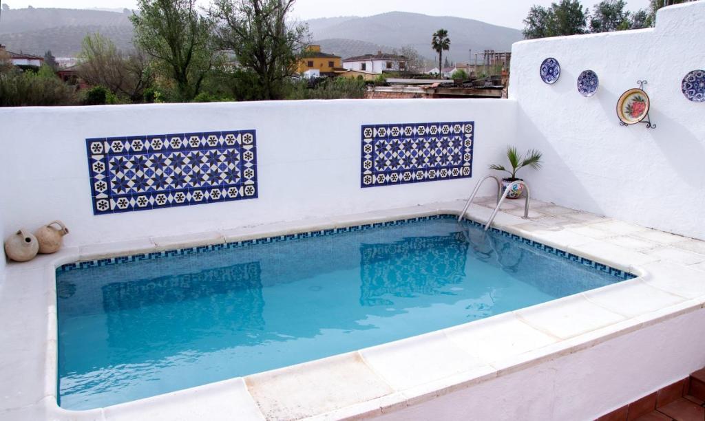 a swimming pool with blue and white tiles on a white wall at Casa rural El Tejar in Villacarrillo