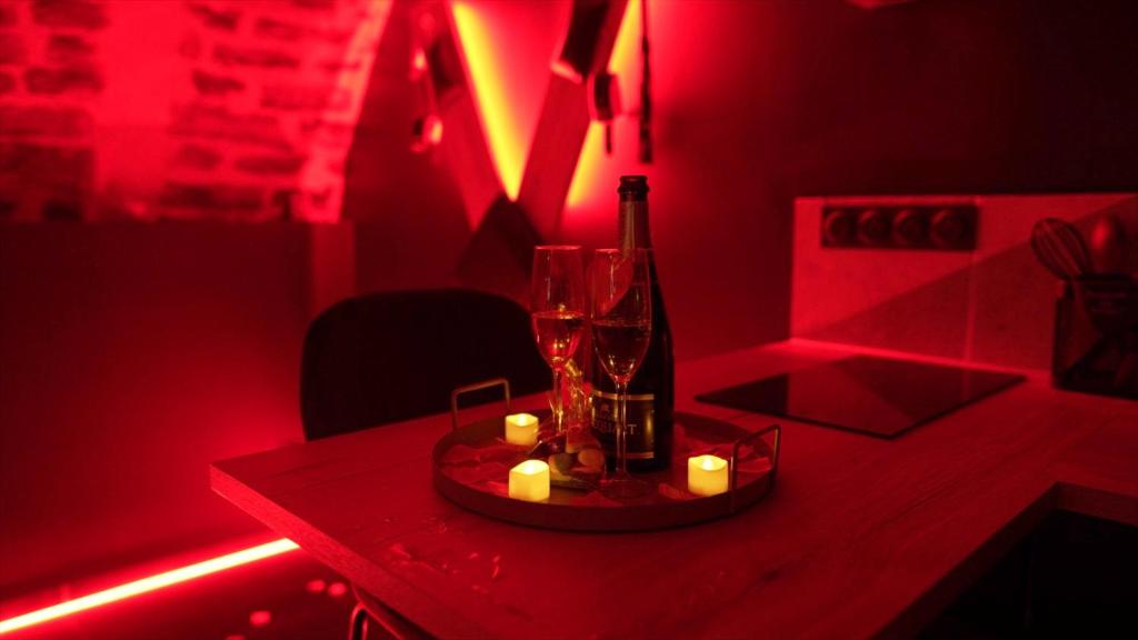 a red room with a bottle and candles on a table at Hébergement insolite, Night Secret Groot in Millau