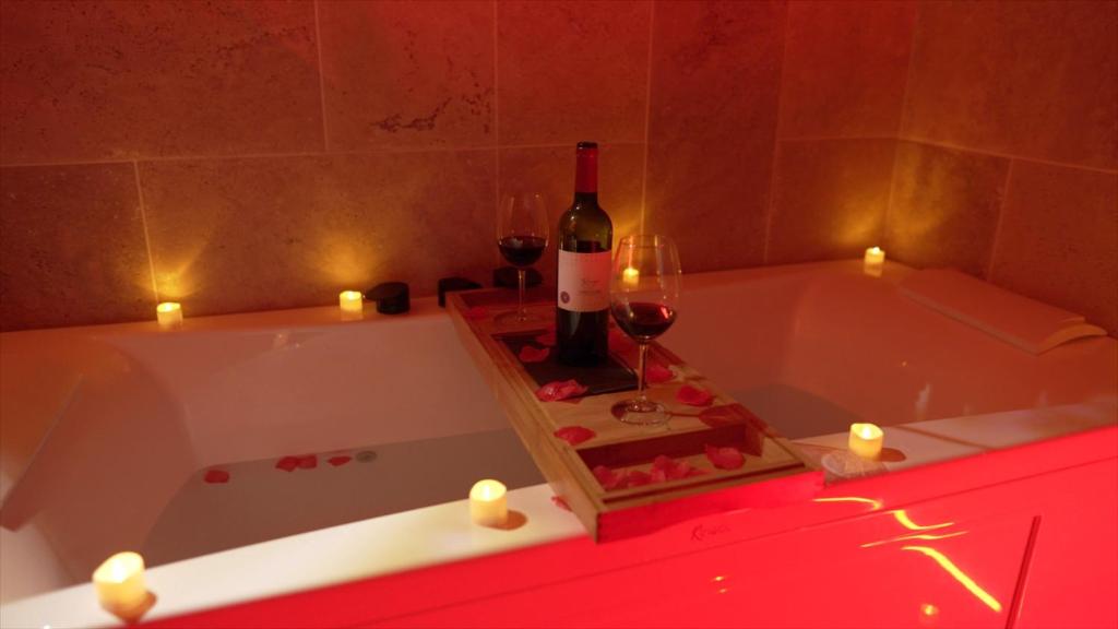 a bath tub with a bottle of wine and candles at Hébergement insolite, Night Secret Groot in Millau