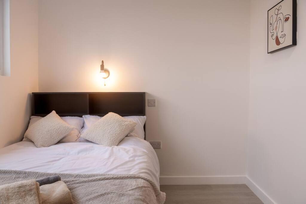sypialnia z łóżkiem z białą pościelą i poduszkami w obiekcie Homely Studio: Old Trafford w Manchesterze