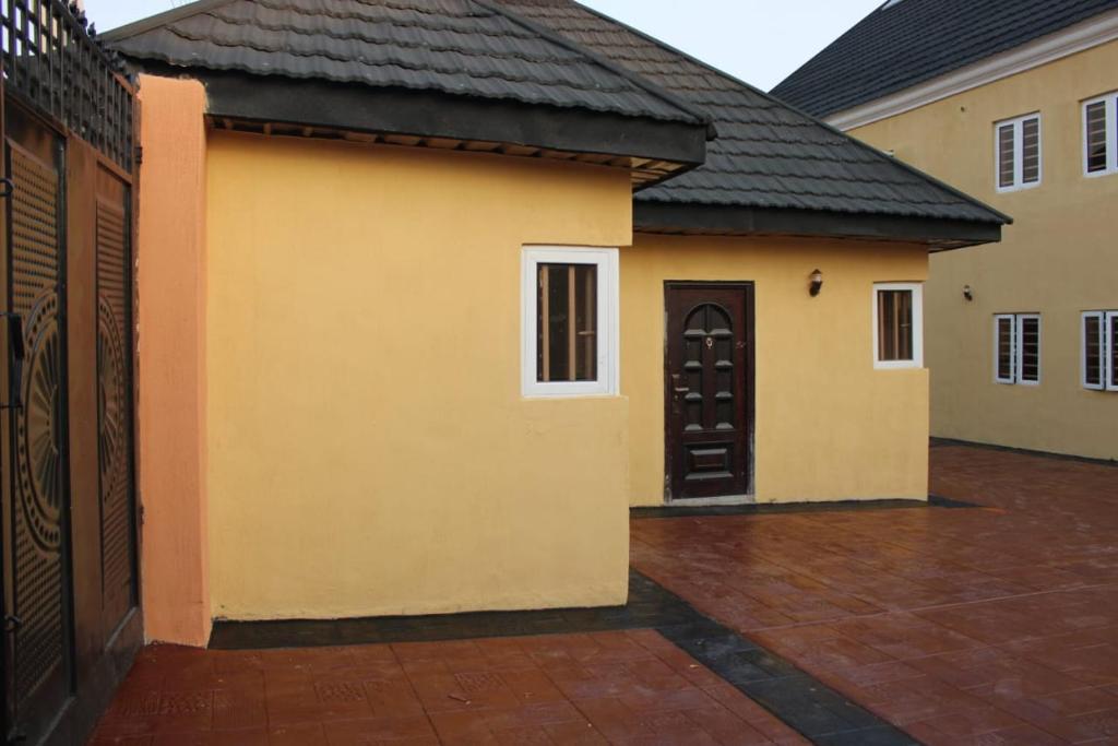 ein gelbes Haus mit einer schwarzen Tür und einem Innenhof in der Unterkunft ODTC Homes and Apartments in Ibadan