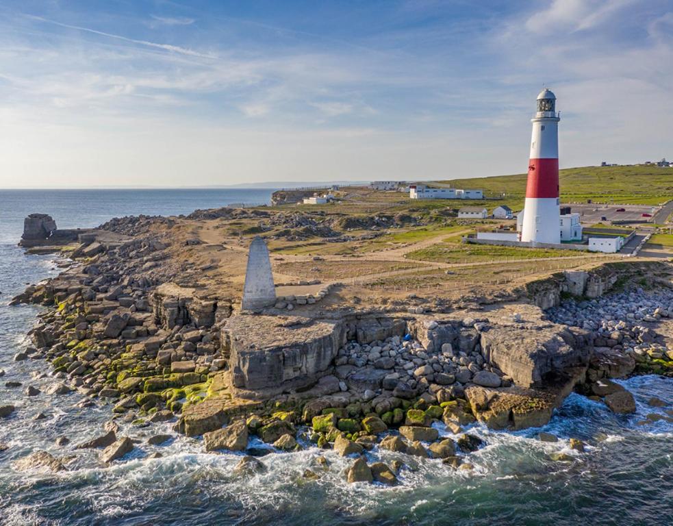 a lighthouse on a rocky island in the ocean at PennWay House - Two Bedroom House on Portland Bill with Sea Views! in Southwell