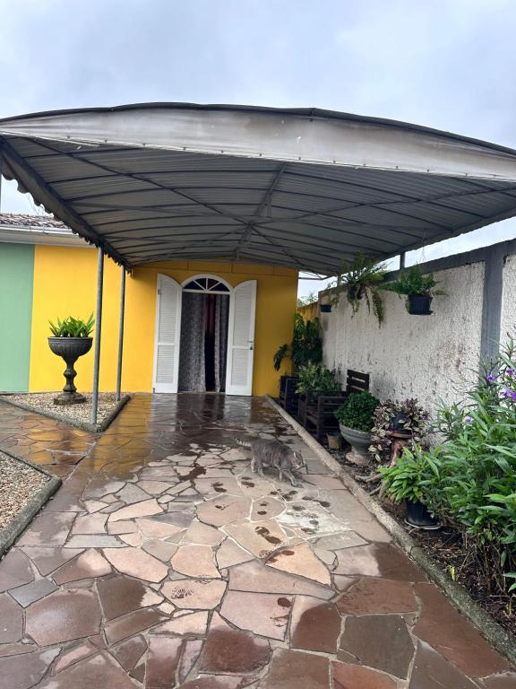 a patio with a black canopy in front of a house at La vita hospedaria (quarto amarelo) in Nova Veneza