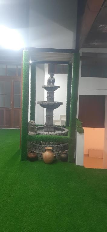 Taita wasi في كاخاماركا: نافورة في وسط غرفة بها عشب أخضر