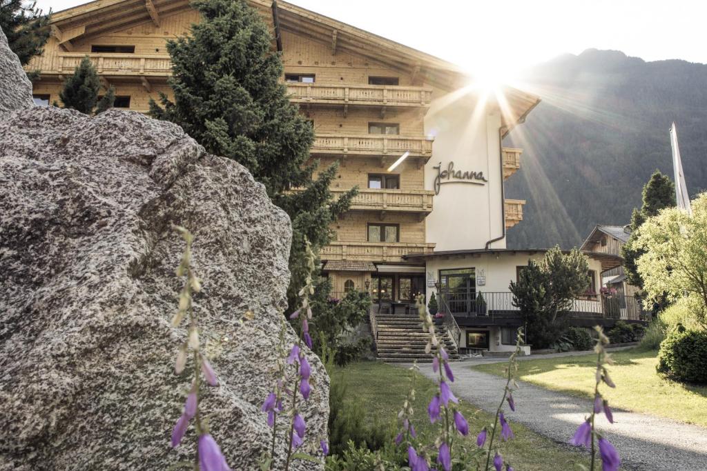 a building in the mountains with purple flowers in front of it at Hotel Johanna mitten im Ötztal SUPERIOR in Umhausen