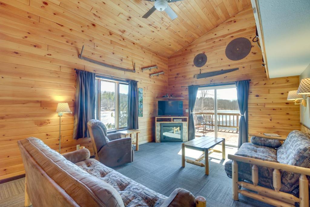 een woonkamer in een blokhut met een bank en een tv bij Park Rapids Cabin with Fire Pit and Lake View! in Arago