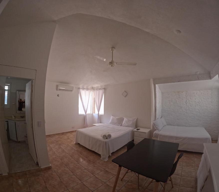 a bedroom with two beds and a table and a window at Hotel El Legendario in Sosúa