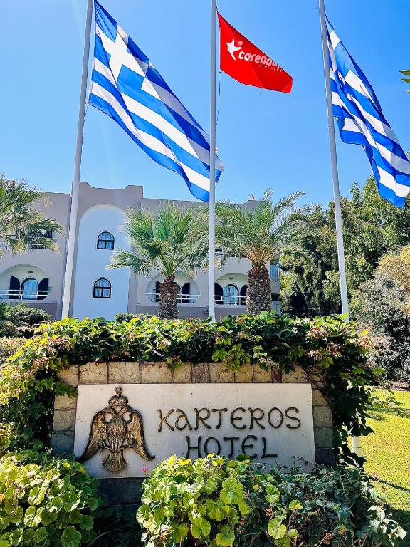 two flags and a sign in front of a hotel at Karteros Hotel in Karteros
